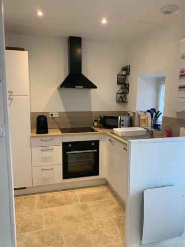 a kitchen with white cabinets and a stove top oven at La petite Bretonne in Plounérin