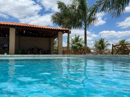 a swimming pool with a house and palm trees at Sítio recanto das Palmeiras in Serrinha