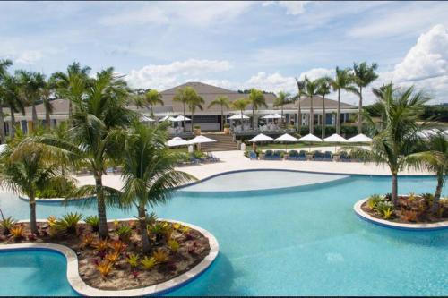 a resort pool with palm trees and umbrellas at Aconchegante casa na represa. in Itaí