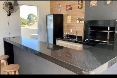 a kitchen with a counter with a sink and a fireplace at Aconchegante casa na represa. in Itaí