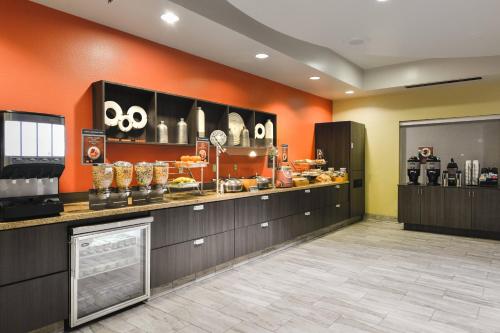 a restaurant with orange walls and a counter with food at SpringHill Suites Shreveport-Bossier City/Louisiana Downs in Bossier City