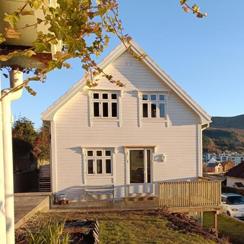 une maison blanche avec une terrasse couverte et une cour dans l'établissement Charming house in Ulsteinvik with free parking, à Ulsteinvik