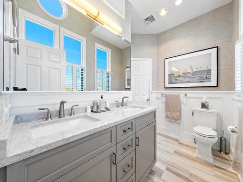 a bathroom with a sink and a toilet and windows at Beautifully Renovated Ocean Front Home In Harvey Cedars in Harvey Cedars