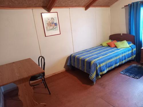 niewielka sypialnia z łóżkiem i stołem w obiekcie HOSPEDAJE POR TEMPORADA VERANO COYHAIQUE w mieście Coihaique
