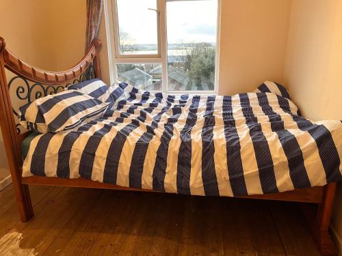 a bed with a checkered comforter and a window at A place to stay in Purfleet