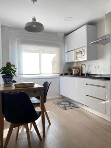 een keuken met witte kasten en een tafel en stoelen bij Casa La Victoria in Málaga