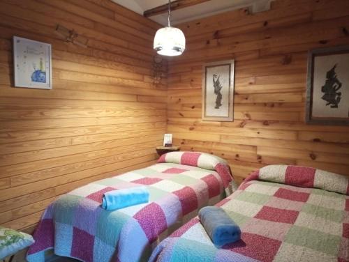 two beds in a room with wooden walls at La Casa Del Teix in Eslida