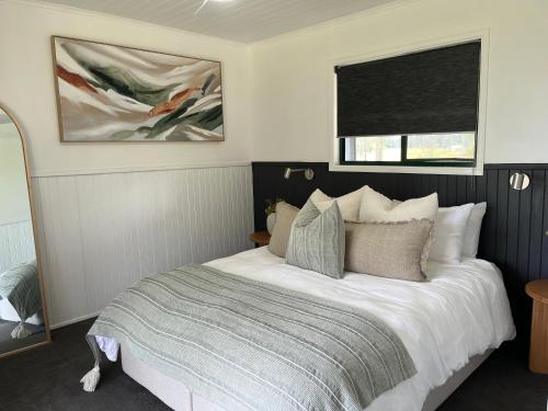 a bedroom with a bed with white sheets and a window at Cabins at Lovedale Wedding Chapel in Lovedale