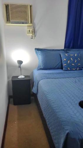 a bedroom with a blue bed with a lamp on a night stand at Casa Bangtan in Florianópolis