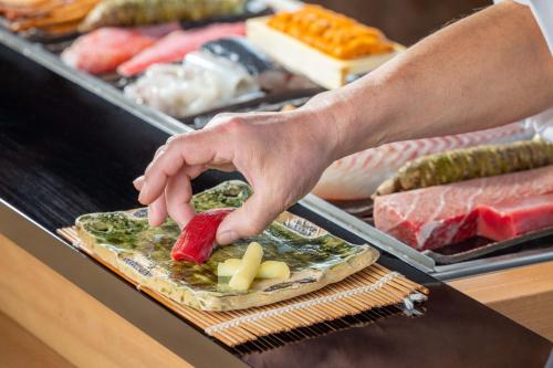 a person holding a piece of meat on a grill at Nagoya Marriott Associa Hotel in Nagoya