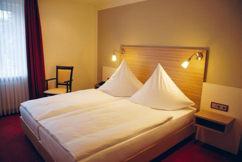 ein großes weißes Bett in einem Hotelzimmer in der Unterkunft Hotel Mühleneck in Schortens