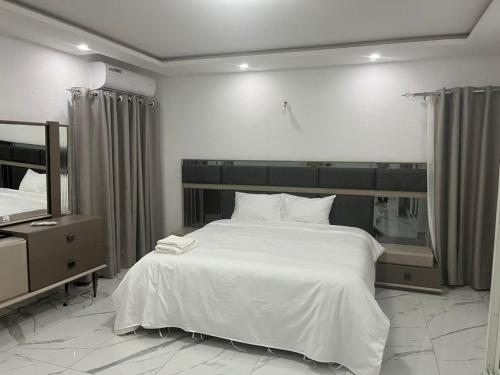 a bedroom with a large white bed and a mirror at Residence Roume Abidjan Plateau in Abidjan