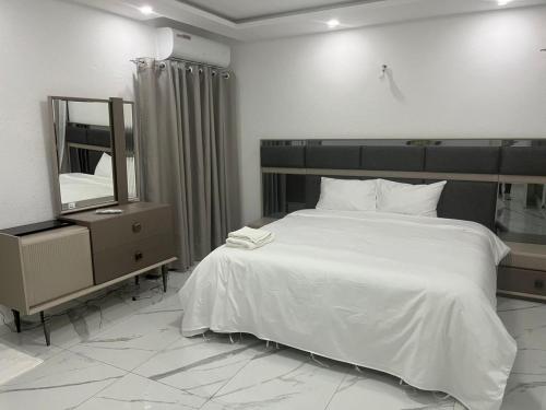 a bedroom with a large white bed and a mirror at Residence Roume Abidjan Plateau in Abidjan