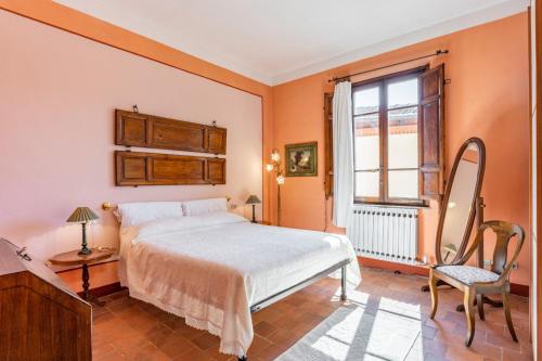 1 dormitorio con cama, ventana y silla en Appartamento in villa liberty, en Ghivizzano