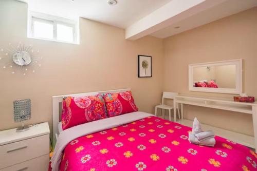 1 dormitorio con cama rosa y espejo en Charming 2-BDR Apt, Private Entrance, Self Check-in, en Toronto