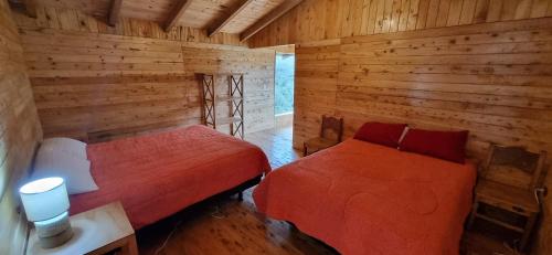 a bedroom with two beds in a log cabin at Espeletia Lodge in El Ángel