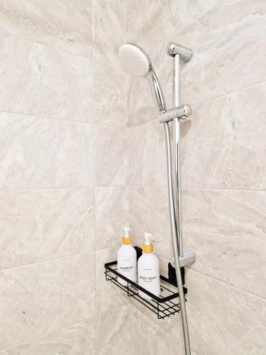 La salle de bains est pourvue d'une douche avec deux bouteilles de shampoing sur une étagère. dans l'établissement CHARMING APARTMENT WITH PANORAMIC SEINE RIVER & EIFFEL TOWER VIEWs, à Ivry-sur-Seine