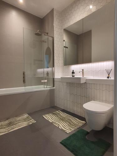 uma casa de banho com um WC, um chuveiro e um espelho. em Cozy Room with Private Bathroom in Luxurious Flat em Londres
