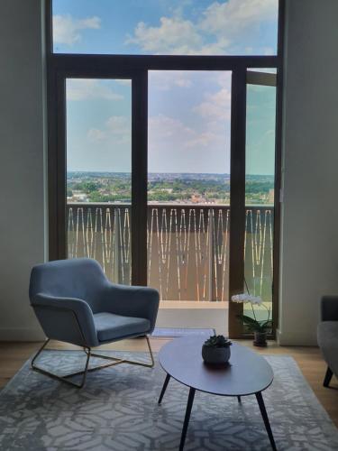 uma sala de estar com uma cadeira, uma mesa e uma grande janela em Cozy Room with Private Bathroom in Luxurious Flat em Londres