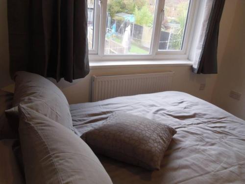 a bed with a pillow in front of a window at House in Great Barr, with parking and garden in Birmingham