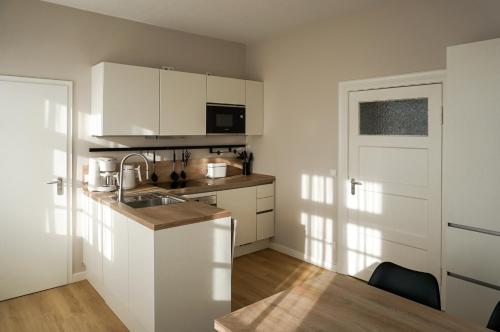 a kitchen with white cabinets and a sink at Mollibahnhof - Kühlungsborn West Mollibahnhof West - Ferienwohnung 01 in Kühlungsborn