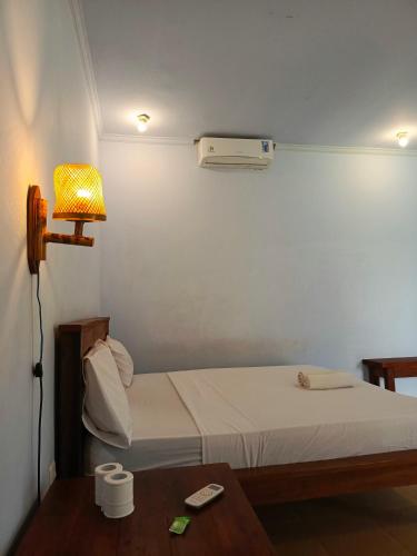 a room with a bed and a lamp and a table at Mengalung Bungalow in Kuta Lombok