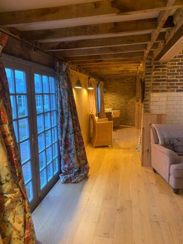 a living room with a couch and large windows at The Cowshed - converted barn/dairy in Felbridge