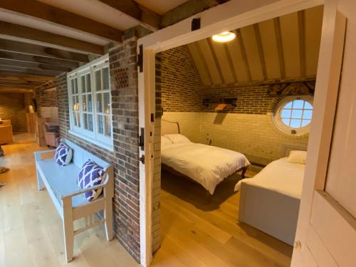 a room with two beds and a brick wall at The Cowshed - converted barn/dairy in Felbridge