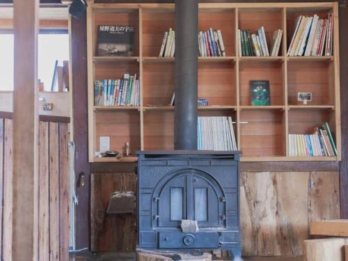 um fogão numa sala com uma estante de livros em "八ヶ岳山麓の小さな家" em Hara