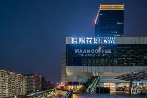 a large building with a sign on it at night at Wuyu Sky Garden Hotel Chongqing Zoo & Yangjiaping The Mixc Light rail in Chongqing