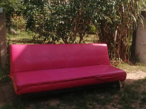 a red couch sitting outside in the grass at Per a Tu in Punta del Este