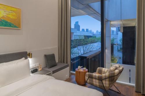 - une chambre avec un lit, une chaise et une fenêtre dans l'établissement Wuyu Hotel Chongqing Yangjiaping The Mixc, à Chongqing