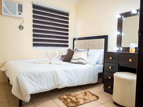 a bedroom with a white bed with a dresser and a window at Affordable 2 Bed Condo Rental in Davao City with Wifi & Netflix, Swimming Pool, Gym & Billiard Hall in Davao City