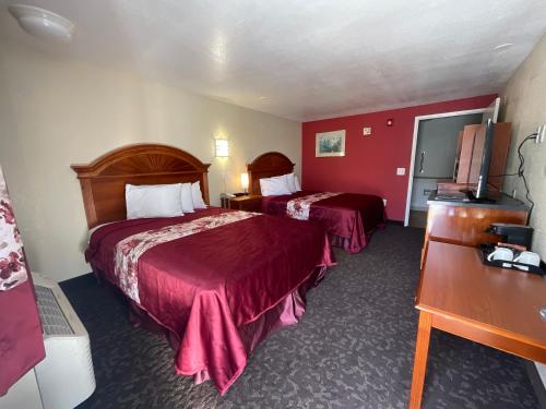 two beds in a hotel room with red walls at Knights Inn Punta Gorda in Punta Gorda
