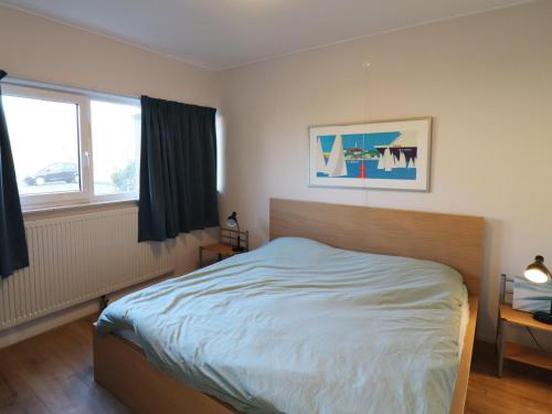 a bedroom with a bed and two windows at Sunny apartment directly on the Heegermeer in Heeg