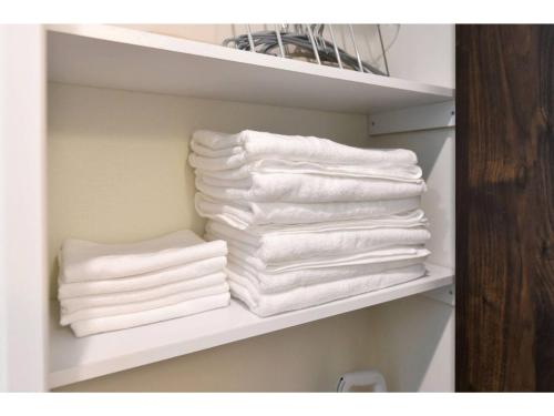 uma pilha de toalhas numa prateleira na casa de banho em Hinata-an Sakura - Vacation STAY 86850 em Yufu