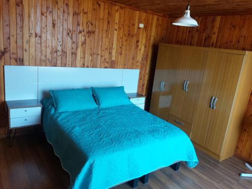 1 dormitorio con 1 cama azul y paredes de madera en Casa Chonchi, Chiloé en Chonchi