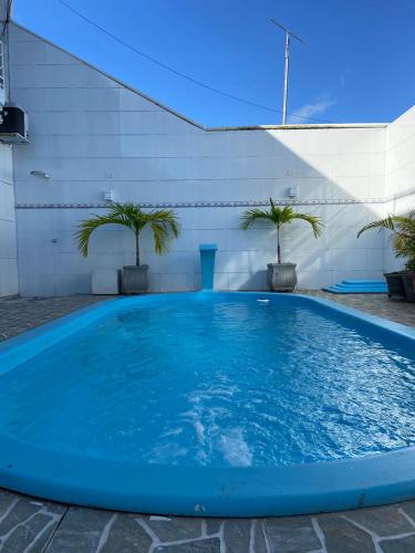 une grande piscine bleue avec deux palmiers dans l'établissement Casa do sol - Marechal, à Marechal Deodoro