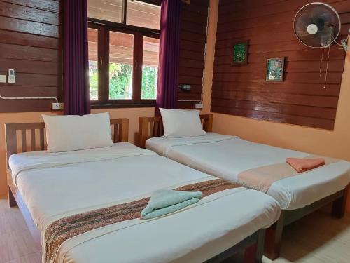 Duas camas num quarto com paredes e janelas de madeira em ต้นพร้าวรีสอร์ท Ton prao Resort 