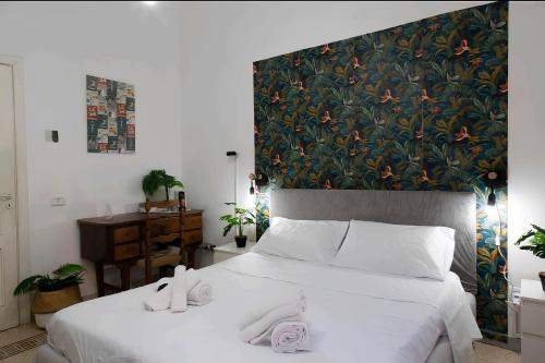 una camera da letto con un grande letto bianco con una parete floreale di Grey Room 'Historic Centre' a Napoli