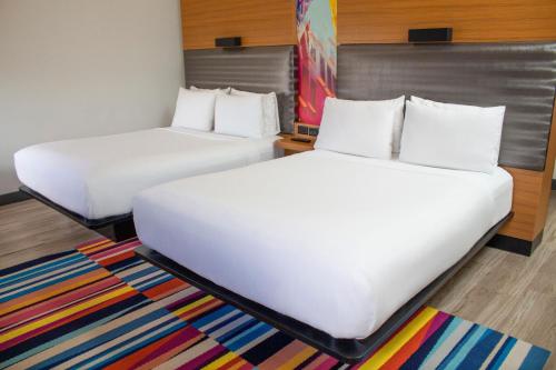 two beds in a room with a colorful rug at Aloft Miami Doral in Miami