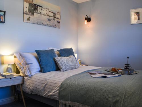 1 dormitorio con cama con almohadas azules y escritorio en Pike Cottage, en Hinderwell