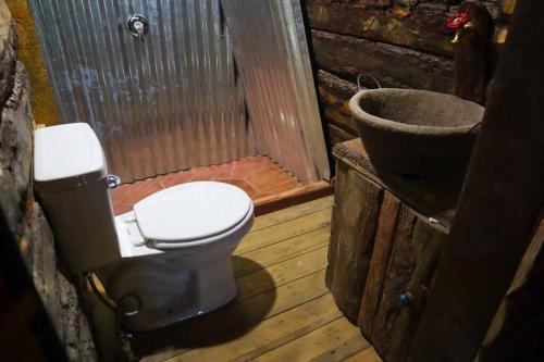 a bathroom with a toilet in a cabin at Fuego - Wood Cabin Tecpan (No Wifi, Relax) in Tecpán Guatemala