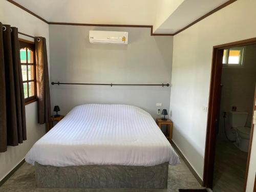 1 dormitorio con cama blanca y baño en Mister check paradise, en Si Chiang Mai