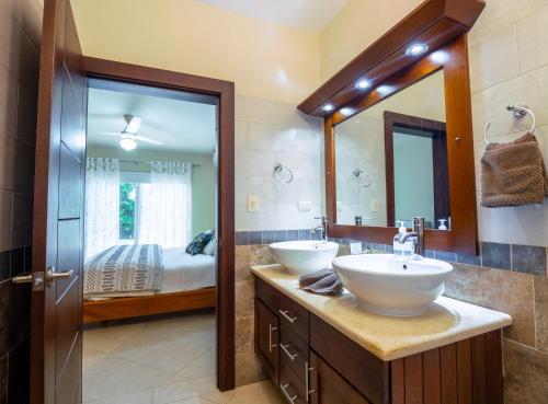 La salle de bains est pourvue de 2 lavabos et d'un grand miroir. dans l'établissement Chic Villa with King Room BBQ Pool Restaurant Shuttle, 