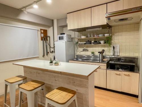 大阪的住宿－TasoneUrbanStayOsaka なんば日本橋三陽グリーンハイツ203，厨房配有带凳子的柜台和冰箱。