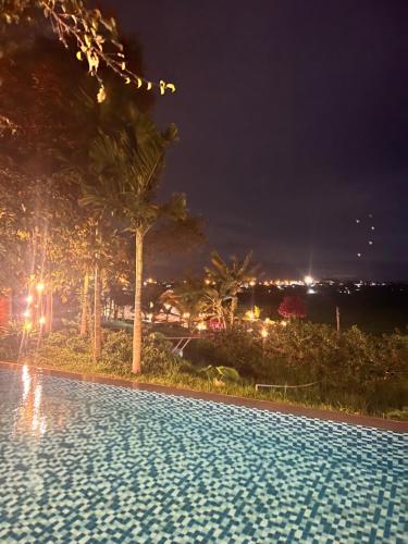 a swimming pool at night with palm trees at Komleo Farm in Buôn Kô M'lêo