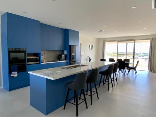 une cuisine aux murs bleus et un comptoir avec tabourets de bar dans l'établissement Koopalanda Dreaming, à Vivonne Bay