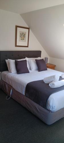 a bedroom with a large bed with purple and white pillows at 1 St James in Hanmer Springs