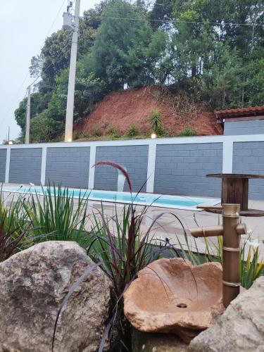 a garden with a fountain and rocks and a pool at Recanto do Príncipe, privacidade, paz e contato Com a natureza in Marechal Floriano